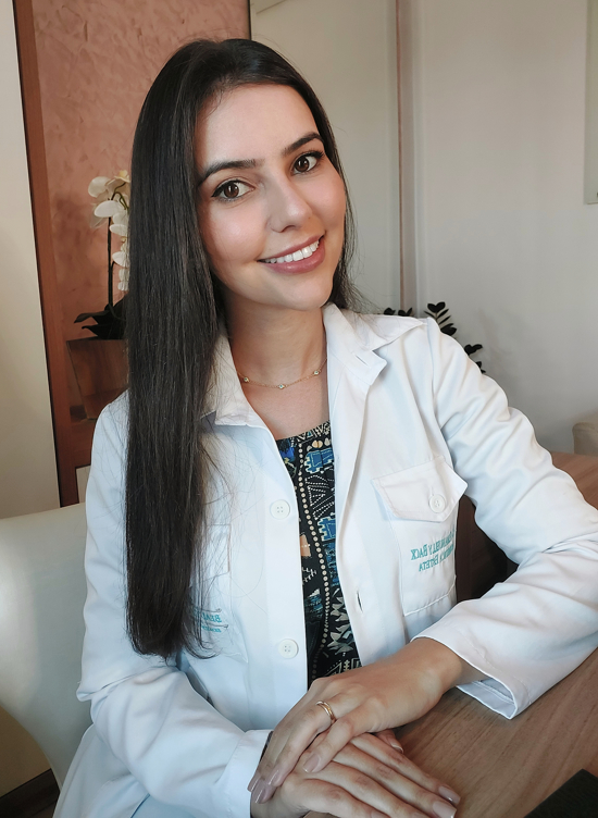 Dra. Emanuelly Back de jaleco em sua clínica